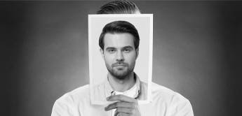 black and white image of person holding piece of paper infront of their face with a headshot of a different person.